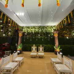 A close-up of the mandap seating, with traditional chairs for the bride and groom set under a canopy of white and yellow flowers.
