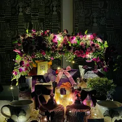The housewarming hamper illuminated by fairy lights, creating a magical and inviting glow. This view highlights the stunning floral centerpiece against a dark background.