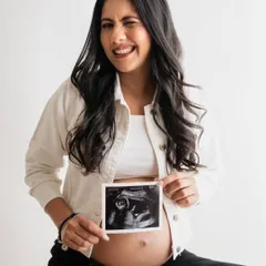A little wink for the camera! Holding up the ultrasound photo is the classic and most heartwarming way to announce you're expecting. This mom-to-be's playful expression makes the shot extra special.
