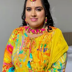 A beautiful portrait of the Haldi bride. Her makeup is minimal yet impactful, with a focus on fresh skin and a pop of color on the eyes to match her floral accessories.