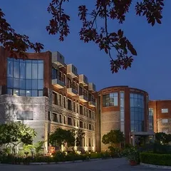 An evening view of the ISID campus. Proper lighting design is crucial in public architecture to ensure safety and create a welcoming ambiance. Here, it highlights the textural quality of the brick and stone facade.