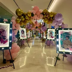 For this event entrance, I created a walkway lined with the couple's photos displayed on easels with built-in lights. The path is decorated with a balloon arch in gold, pink, and purple.