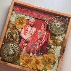 A beautiful example of varmala and kalire preservation in a wooden tray. The couple's photo and the red border from their wedding attire are also incorporated into the design.