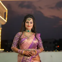 For my sister Sushma's reception, we went for a glamorous and sophisticated look. I created a soft glam eye with a hint of shimmer and a bold lip, paired with a modern half-up hairstyle with loose waves. This style perfectly complemented her elegant purple and gold saree and the evening's celebratory atmosphere.