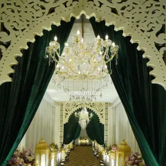 A grand entrance sets the tone for an exceptional event. For this evening gala, we created a stunning entryway with lush green velvet drapes, intricate laser-cut arches, and magnificent crystal chandeliers to welcome guests into a world of elegance.