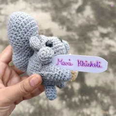 Our crochet squirrel, seen from the side, holding its little nut. We can even add a small, personalized message tag to make your gift extra special.