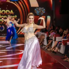 A performer in a shimmering silver outfit during her belly dance routine. The photo captures the flow of the fabric and the joy in her performance.