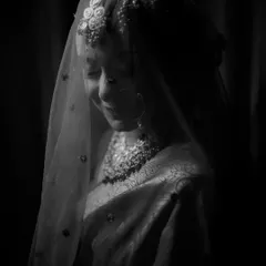 A soft and ethereal black and white portrait of a bride under her veil, capturing a moment of quiet grace.