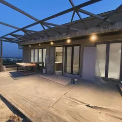 This is a behind the scenes look at a large terrace project in progress. You can see the metal framework for a glass roof being installed, an architectural feature that will create a stunning, all-weather outdoor living area.