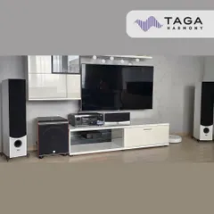 A clean and modern living room setup featuring Taga Harmony tower speakers in white. This system provides a full-range audio experience for both music and movies, integrating well with the contemporary furniture.