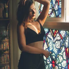 The interplay of light and shadow against a stained-glass window creates a dramatic and colorful effect. This portrait is a great example of using unique lighting to craft a cinematic and memorable image.