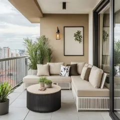 This high-rise apartment balcony features a custom L-shaped sofa with neutral, all-weather fabric, maximizing seating in a compact area. The design is complemented by potted palms and a modern wall sconce, creating a clean and elegant outdoor living space.