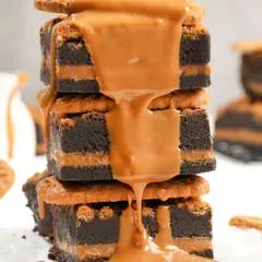 An action shot of rich caramel sauce being poured over a stack of Biscoff brownies. Dynamic shots like this are highly engaging and effective for social media marketing.