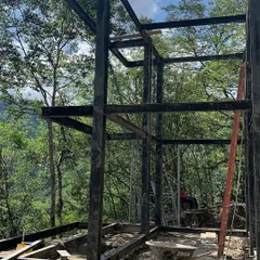 The robust steel skeleton of a two-story modular home under construction in a forest setting. This is the strong foundation upon which we build our durable and long-lasting structures.