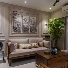 This cozy living room retreat features elegant molding on the walls and inviting wooden and rattan furniture. The beige and indigo blue color palette creates a perfect blend of comfort, personality, and sophistication.