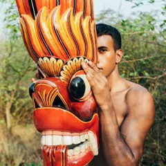 A striking image from the 'Nazaar' series, where a model's face is partially obscured by a large, colorful traditional Sri Lankan mask.