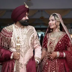 A regal Sikh couple on their wedding day, with the groom holding a kirpan, showcasing the grandeur of Anand Karaj ceremonies.