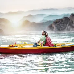 A serene shot of a couple in a traditional boat on the misty waters of Rishikesh. The soft light and calm atmosphere make for a dreamy and romantic pre-wedding picture.