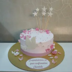 A lovely pink and white confirmation cake. It's decorated with a white dove, stars, and delicate pink flowers.