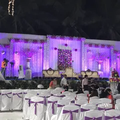A beautiful stage setup for a sangeet or reception at night. The purple uplighting, decorative crystal curtains, and elegant seating create a memorable backdrop for any celebration.