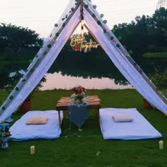 A full view of our romantic picnic setup for two, perfect for a private proposal or anniversary. This arrangement includes a tent, low seating with cushions, and a beautifully set table overlooking the water.