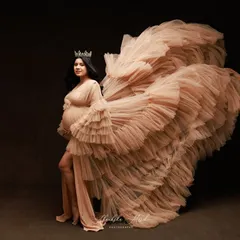 A queen taking flight. The dramatic sweep of this ruffled nude gown creates a sense of power and movement, celebrating the majestic journey of motherhood.