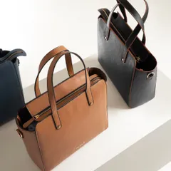 A clean, top-down shot of two structured tote bags in tan and black. This minimalist presentation is perfect for an e-commerce site, showing the product's form and details without distraction.