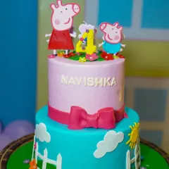 A close-up of the adorable two-tiered Peppa Pig cake, complete with character toppers and a cheerful design.