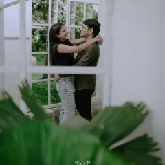 A romantic embrace framed by a window, creating a sense of intimacy and a beautiful, layered composition.