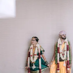A quiet moment captured between the bride and groom, holding hands in their traditional wedding attire and garlands.