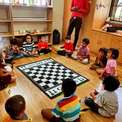A moment of calm before the game begins. In our group classes, we guide students through simple mindfulness exercises. This helps them clear their minds, sharpen their focus, and prepare for strategic thinking around our large floor chessboard.