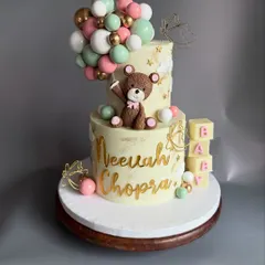 Welcoming a new baby is such a precious moment, and this cake was designed to capture that joy. This two-tier eggless Chocolate-Dulce de leche cake for a naming ceremony features a cute, handcrafted teddy bear, a cascade of chocolate balloons, and personalized details.