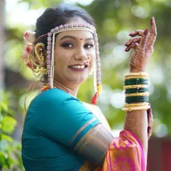 The pure joy of a bride on her special day. This close-up highlights the traditional Maharashtrian bridal accessories, including the 'mundavalya' (forehead ornament), paired with a radiant makeup look that emphasizes her glowing skin and happy smile.