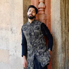 This asymmetric jacket with traditional prints offers a unique silhouette. Paired with a striped kurta, it creates a dynamic look that is perfect for the fashion-forward man.