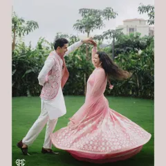 A beautiful, dynamic shot of the groom twirling his bride on a lush green lawn. The movement of her lehenga and their joyful expressions make this a perfect Roka portrait.