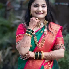 A close-up portrait of a Marathi bride, highlighting her traditional jewelry, green glass bangles, and intricate mehndi.