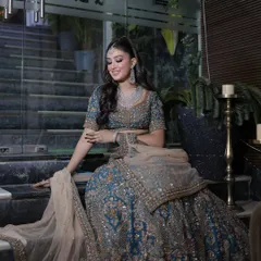 A full-length shot of this glamorous look. The heavily embellished teal lehenga is perfectly balanced by the bold makeup and sleek hair.