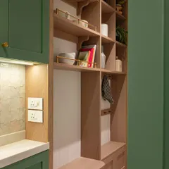 This open shelf, positioned at the kitchen entrance, is more than just storage; it’s a showcase for personality. Styled with artisanal ceramics, cookbooks, and greenery, it creates a natural transition that makes the kitchen feel open and inviting.