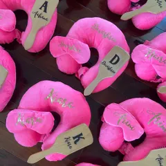 Birthday favors for the little girlies. These personalized travel sets include a bright pink neck pillow, an eye mask, and a custom hairbrush, all with their names in gold.