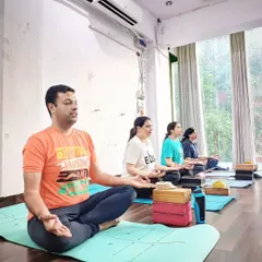 Students sit in a moment of quiet reflection during a group meditation session. Practicing together creates a powerful collective energy that deepens the experience for everyone in the room.