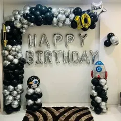An exciting outer space theme set up in a room. The black and silver balloon arch, rocket ship balloon, and "Happy Birthday" letters transform the space for a 10th birthday.
