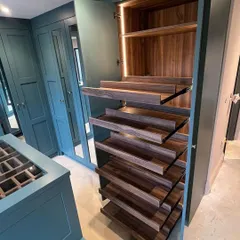 Our custom pull-out shoe storage, shown here within a walk-in closet, is designed for the serious collector. The smooth German hardware ensures effortless access to your footwear.
