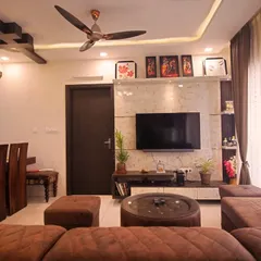 This living room design combines rich wood tones with a comfortable, modern sofa and a unique false ceiling detail, creating a warm and inviting atmosphere.