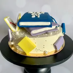 Another angle of the book-themed cake, showing the scattered edible pages and books.