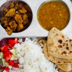 A simple and satisfying meal of paratha and rice. It is served with a dry vegetable dish, our classic dal, and a fresh cucumber and tomato salad.