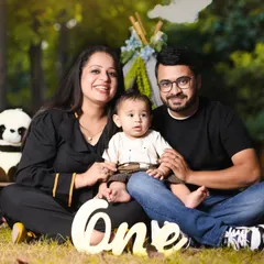 A lovely family photo taken during an outdoor first birthday shoot, with their little one sitting happily between them in front of our teepee setup.