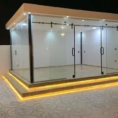 A sleek glass enclosure with sliding barn-style doors, built on a raised platform with integrated step lighting. This design is perfect for creating a modern and stylish poolside cabana or patio room.