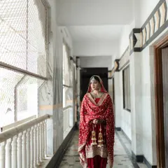 A full-length shot in a beautiful marble corridor. The simplicity of the background makes her traditional red Punjabi suit and jewelry stand out.