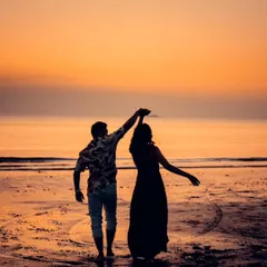 Dancing into the sunset. This silhouette shot captures a moment of pure, uninhibited joy as the couple dances on the wet sand, with the golden sky reflecting on the water. It’s a classic Goa pre-wedding photograph.