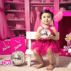 A little girl holds a disco ball during her second birthday Barbie-themed shoot, showing off a fun and playful side.